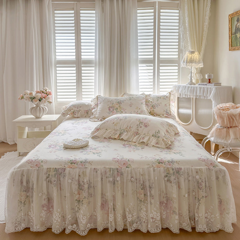 Floral bed skirt on a bed in a bright bedroom with white curtains.