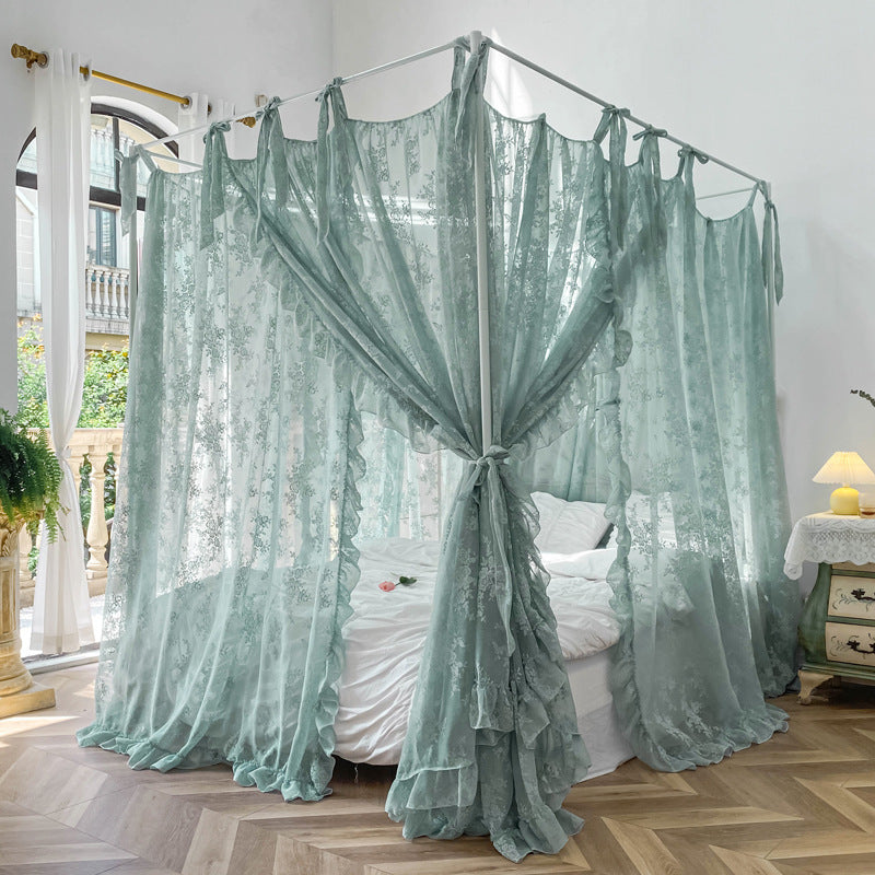 A teal floral lace bed canopy with ruffle trim tied back at the corners, creating a soft and elegant look in a sunny room. The curtains are on a white 4-poster bed frame.