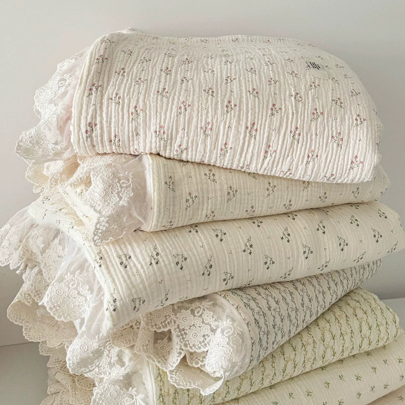 Stack of assorted floral ruffle comforters showing various prints, crinkled cotton texture, and layered lace