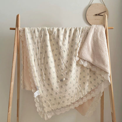 Blue floral ruffle blanket draped over a display rack in a nursery setting, emphasizing soft texture and lace details.