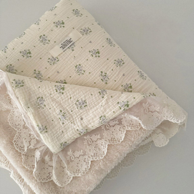 Blue floral print cotton gauze blanket folded to show thick fleece lining and decorative lace ruffle for baby comfort.