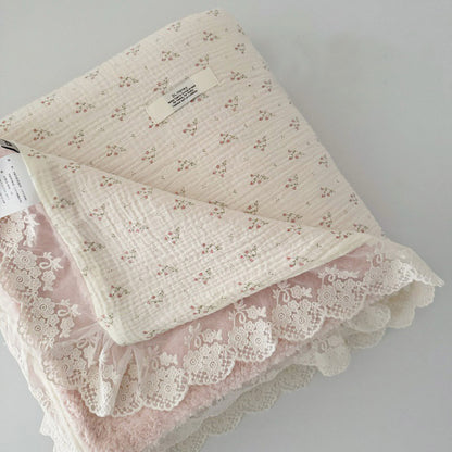 Folded cotton gauze comforter with small pink floral print, showcasing soft pink fleece lining and delicate lace ruffle edge.