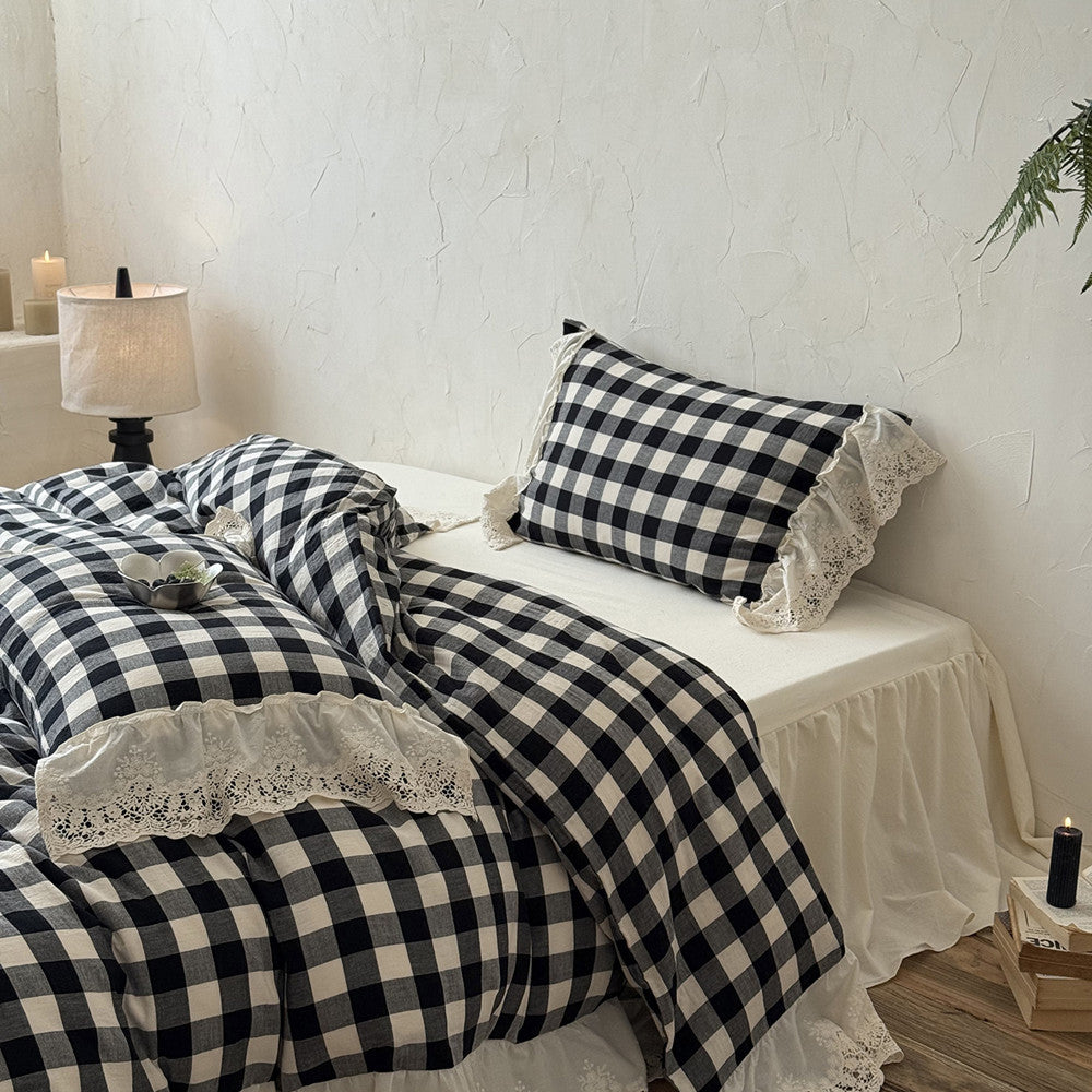 Black and white checkered bedding set with lace details on a bed in a bedroom.