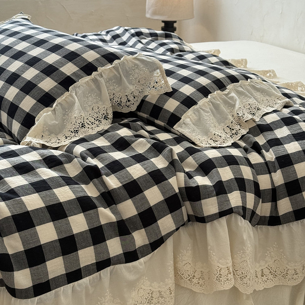 Black and white checkered bedspread with lace trim on a bed.