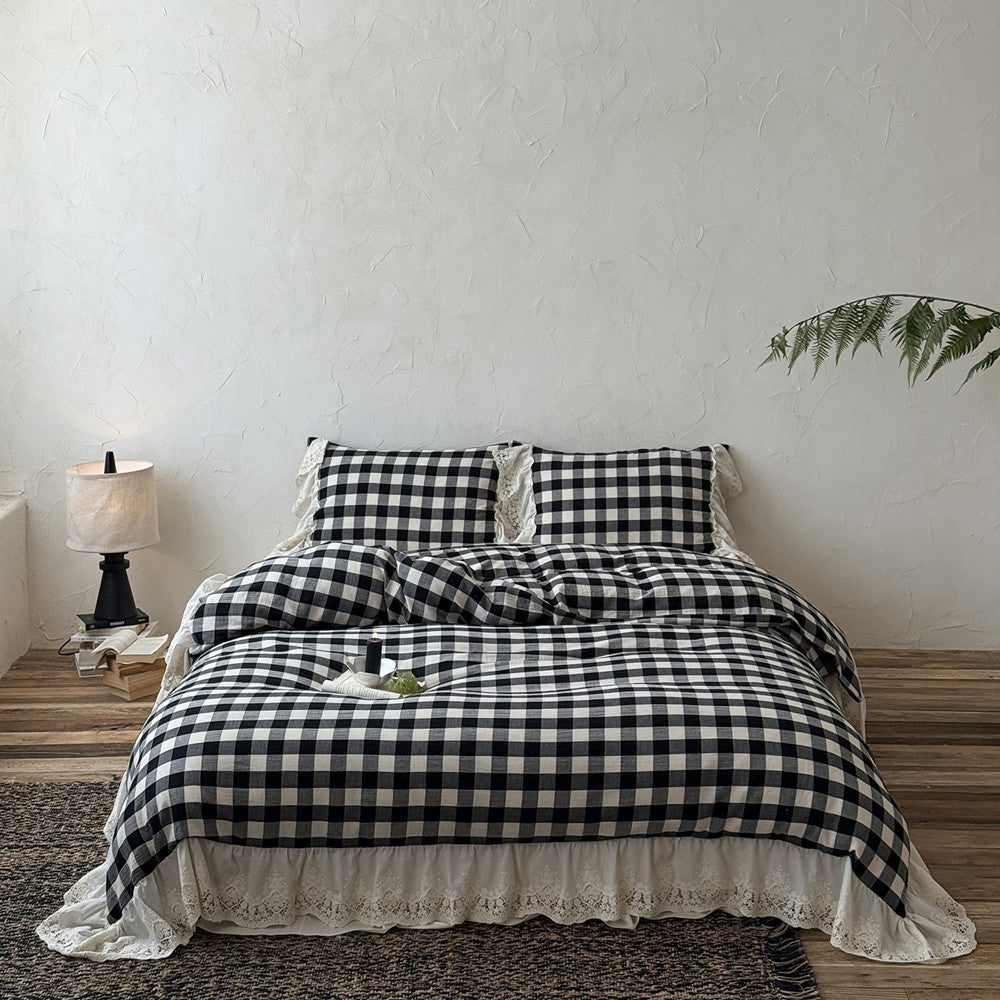 Black and white checkered bedspread on a bed in a room with a lamp and plant.