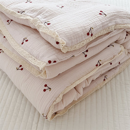 Folded cherry muslin baby quilt showing lace trim