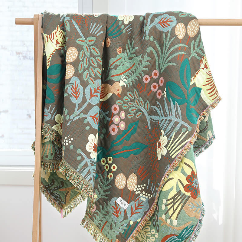 Jungle animal blanket with fringe displayed on wooden rack