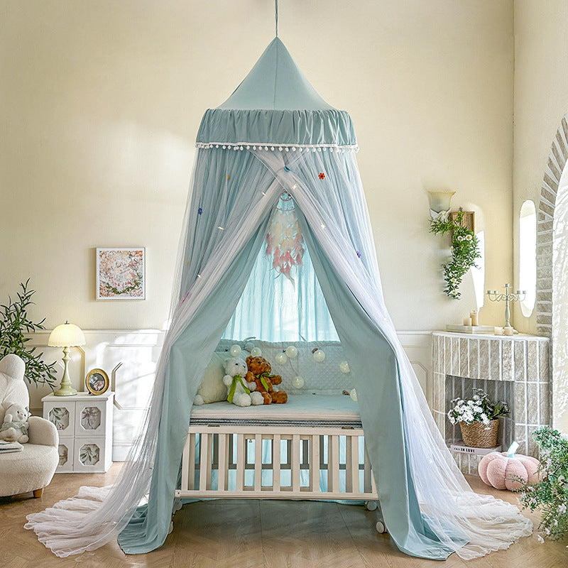 Haze Blue kids bed canopy with a double layer draped design, pom-pom trim, and sheer netting, set up over a white baby crib, perfect for nursery decor.
