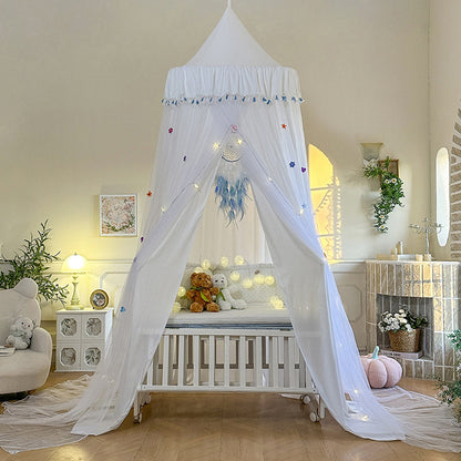Pure White kids bed canopy with blue tassel trim and star decorations, featuring a double layer of sheer tulle, draped over a white baby crib.