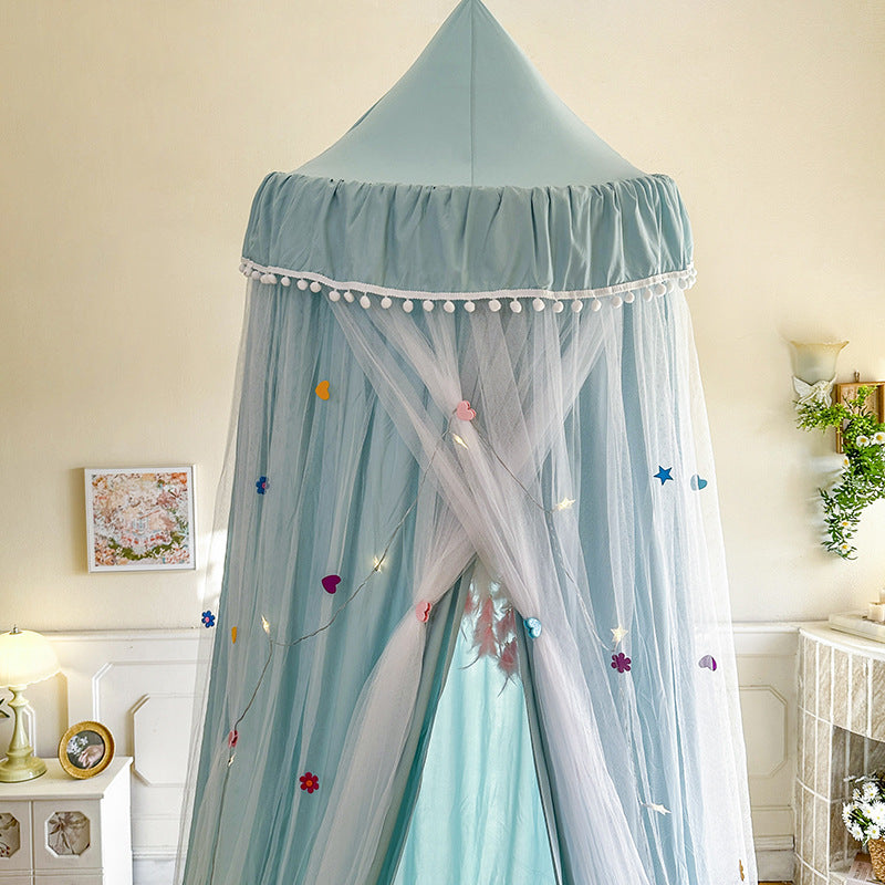 Close-up of the Haze Blue kids bed canopy top, highlighting the white pom-pom trim and the double layer of fabric/sheer mesh decorated with colorful heart and star appliqués.