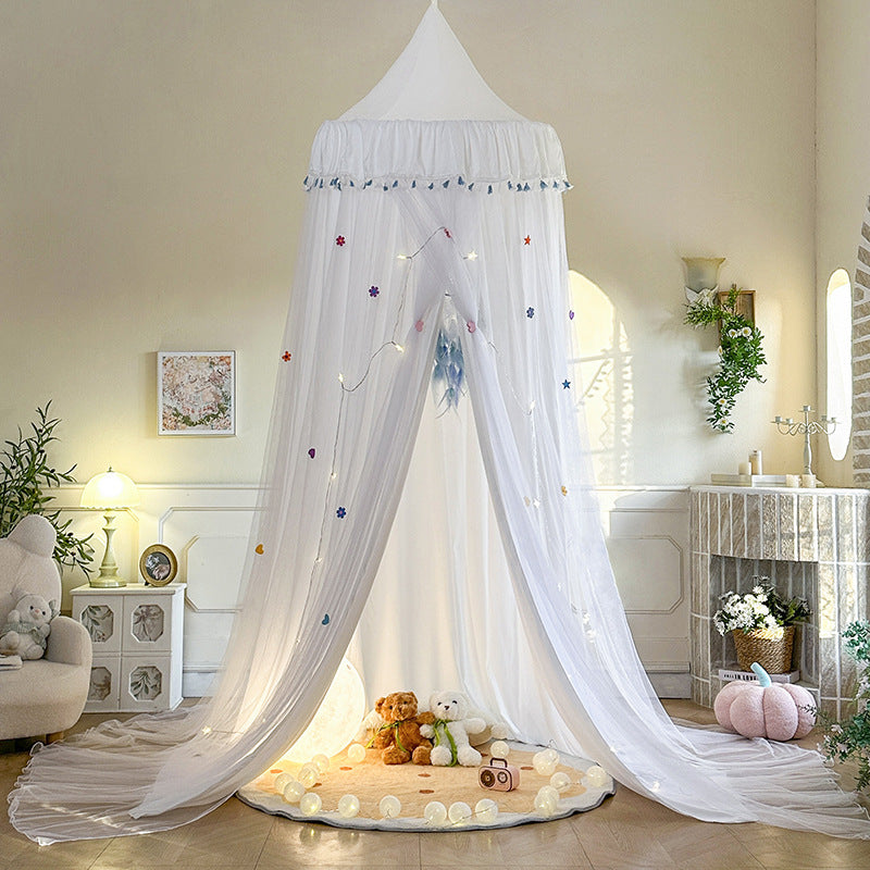 White double-layer kids bed canopy with blue tassel trim, featuring a sheer draped design over a play rug, creating a bright and airy indoor play tent.