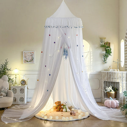 White double-layer kids bed canopy with blue tassel trim, featuring a sheer draped design over a play rug, creating a bright and airy indoor play tent.