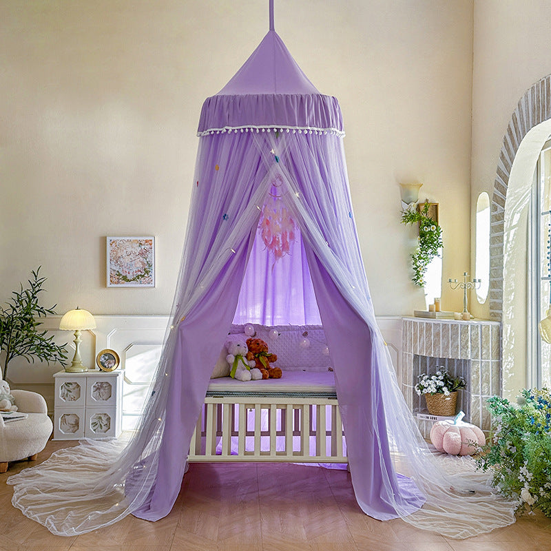 Lavender Purple kids bed canopy with pom-pom trim and double layer draped design, set up over a white baby crib, perfect for a whimsical nursery room.