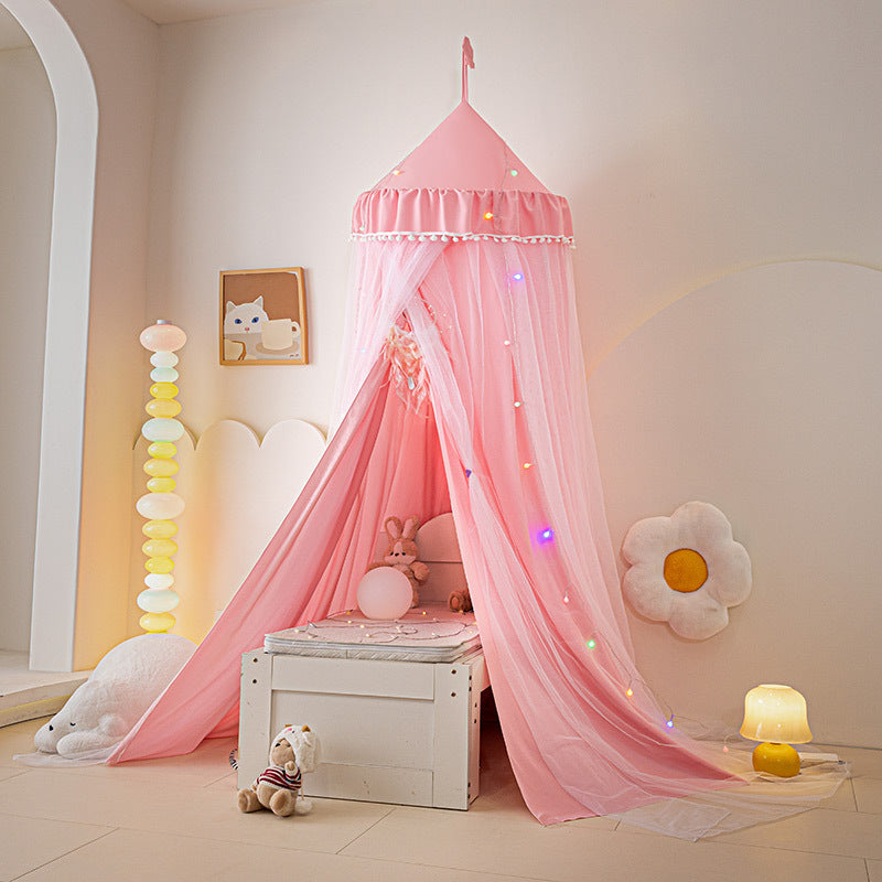 Bright Pink / Hot Pink kids bed canopy tent with pom-pom trim, ruffled top, and hanging sheer mesh, set up indoors over a small white box, ideal for a cheerful princess room theme.