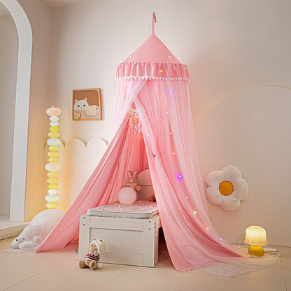 Bright Pink / Hot Pink kids bed canopy tent with pom-pom trim, ruffled top, and hanging sheer mesh, set up indoors over a small white box, ideal for a cheerful princess room theme.