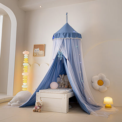 Vibrant Blue kids canopy tent with pom-pom trim and sheer netting, hung as a fun and cozy play tent over a white bed, suitable for a boy's or girl's bedroom.