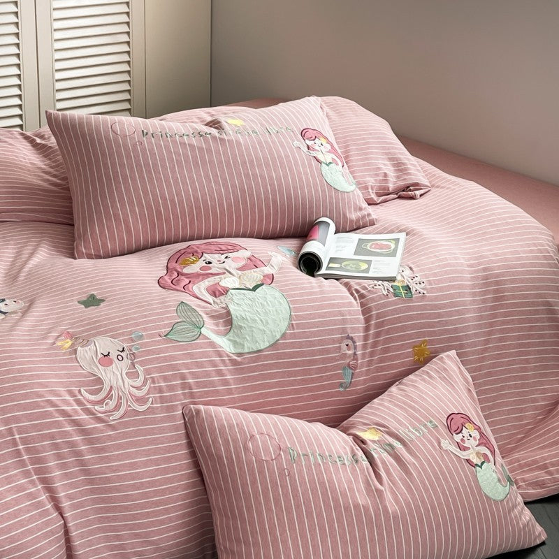 Pink striped bedding set with mermaid designs on a bed.
