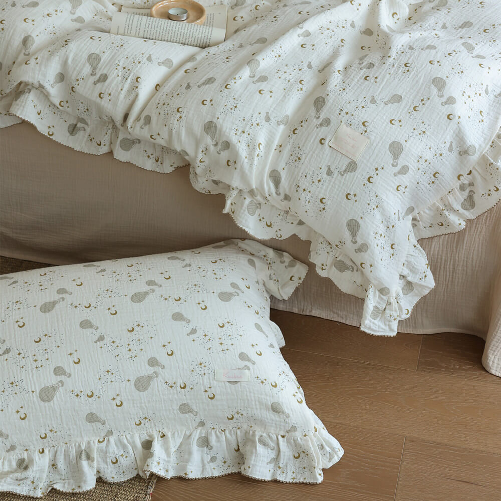 Close-up of cotton muslin moon balloon bedding showing soft texture, neutral print, and ruffled edge detail
