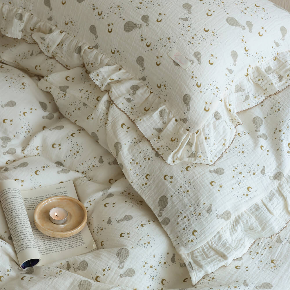 Ruffled pillowcase detail with moon, star, and hot air balloon print on soft cotton muslin fabric