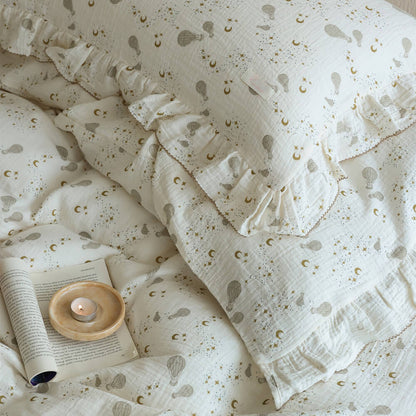 Ruffled pillowcase detail with moon, star, and hot air balloon print on soft cotton muslin fabric