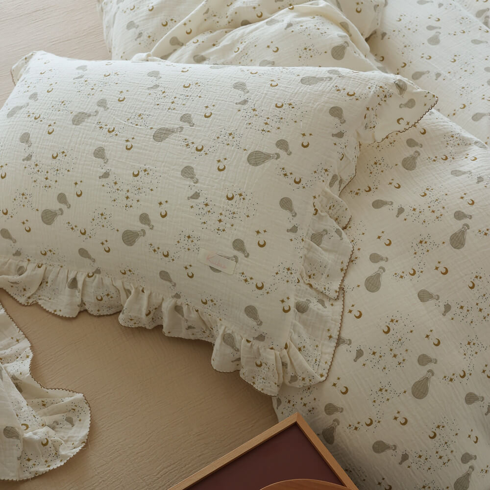 Close-up of moon, star, and hot air balloon print on ivory cotton muslin bedding