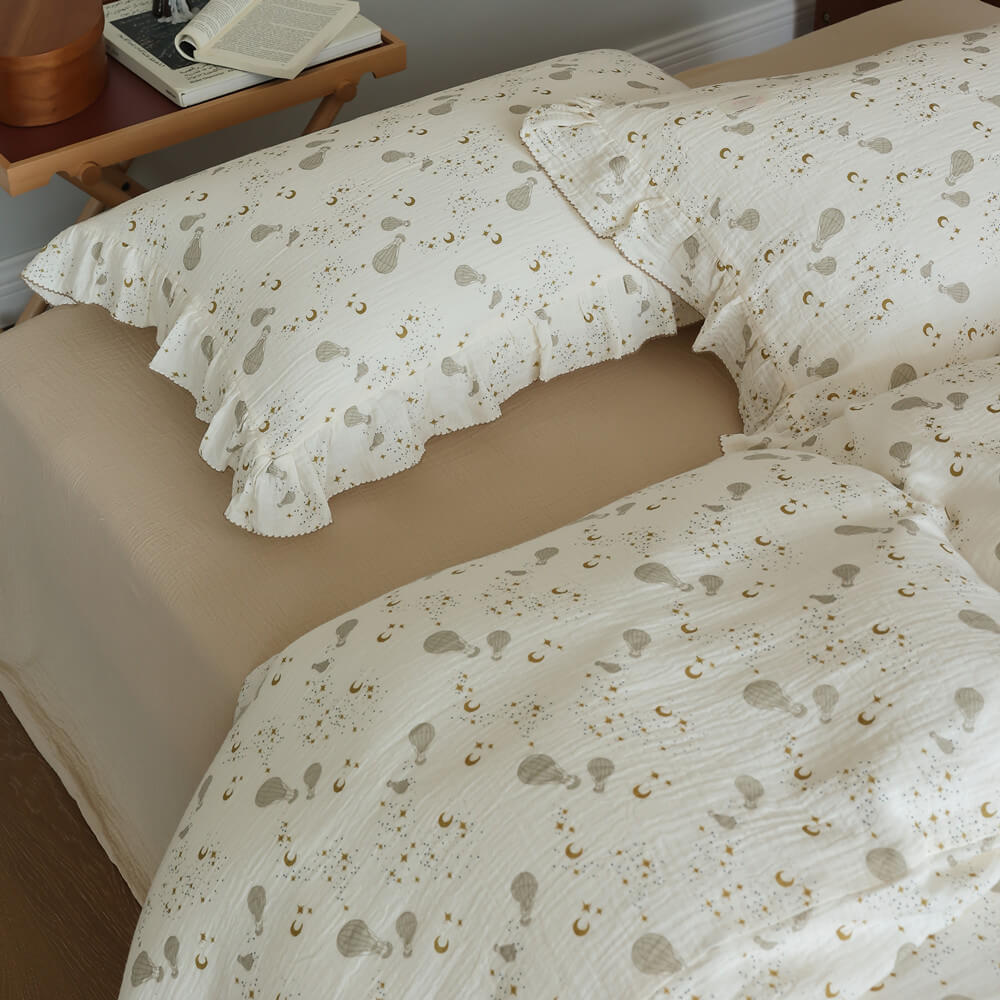 Neutral celestial duvet cover set styled with ivory cotton muslin, ruffled trim, and soft bedroom layers