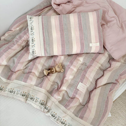 Soft pink striped cotton comforter set and matching pillowcase on a bed, showing the light pink solid reverse side