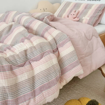 Pink and gray striped comforter on a bed with plush toys.