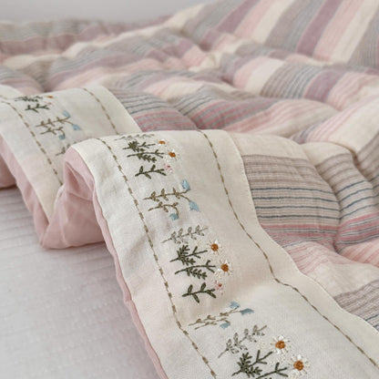 Close-up of a quilt with floral embroidery on a light background