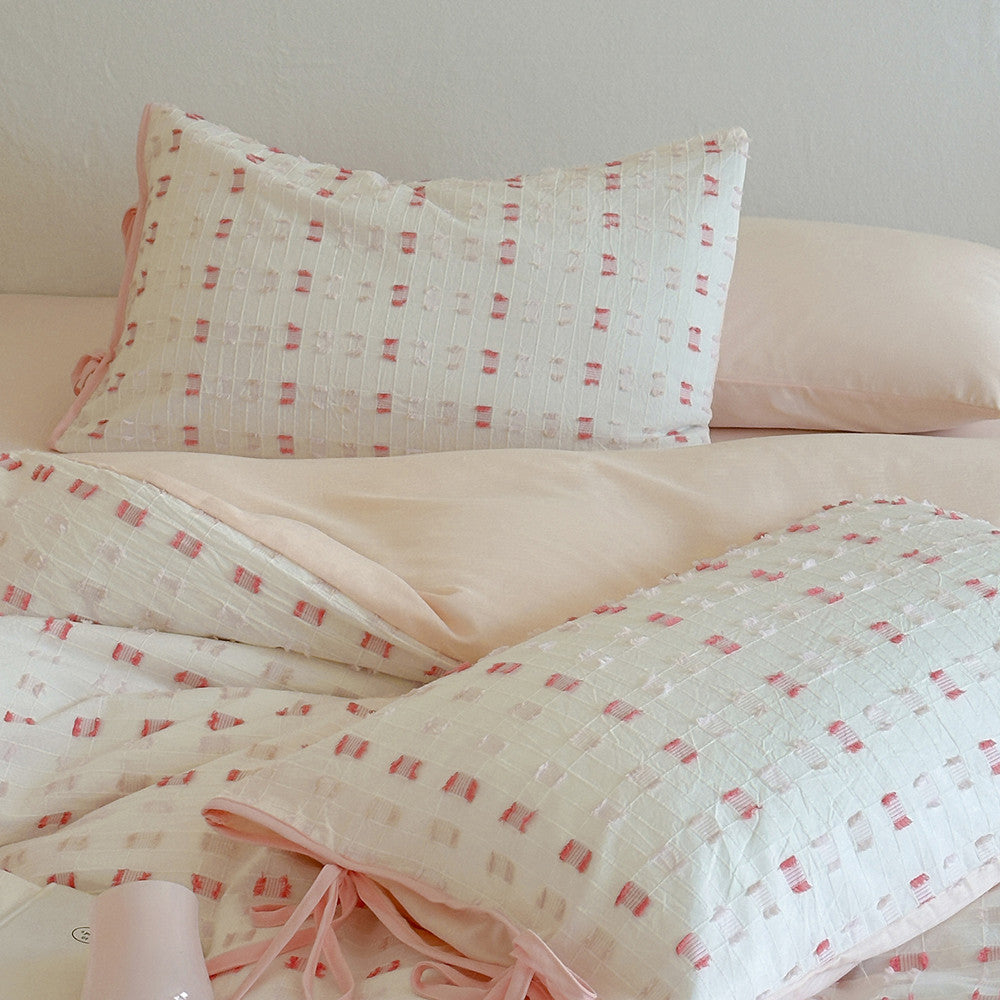 Detailed view of the Pink Tufted Check Cotton Duvet Cover and two matching pillow shams. The image focuses on the subtle pink tufting texture and the solid blush pink reverse side or sheet, emphasizing the quality and soft color palette.