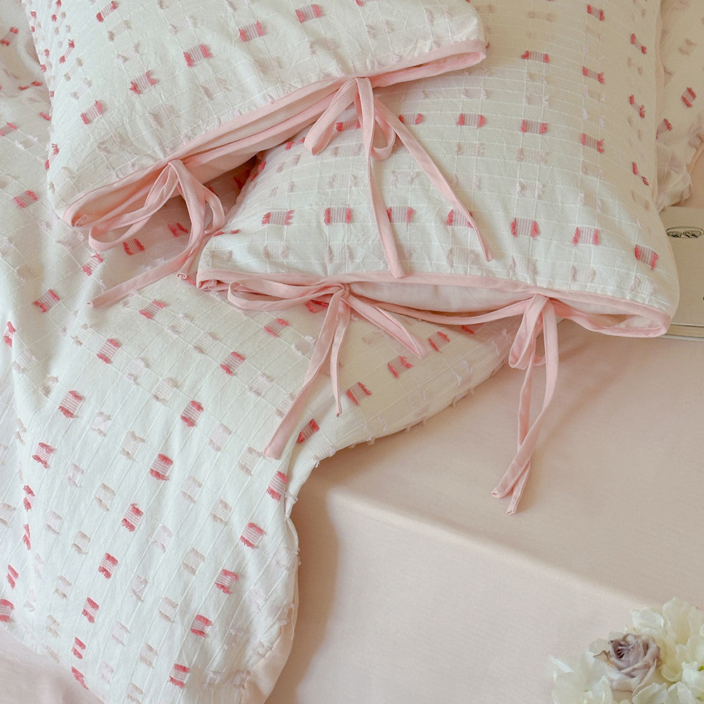 Extreme close-up of the decorative pink ribbon ties on the matching Pink Tufted Check Pillow Sham, showcasing the high-quality 100% cotton material and the intricate tufted check pattern detail.
