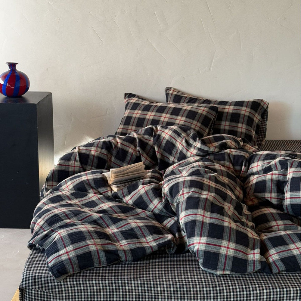 Plaid bedding set on a bed with a minimalistic background