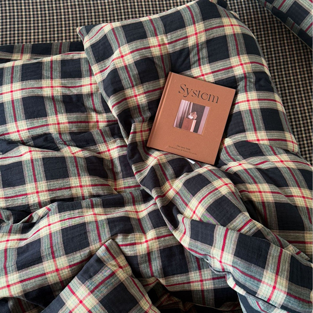 Plaid fabric with a book titled 'System' on top, on a checkered background