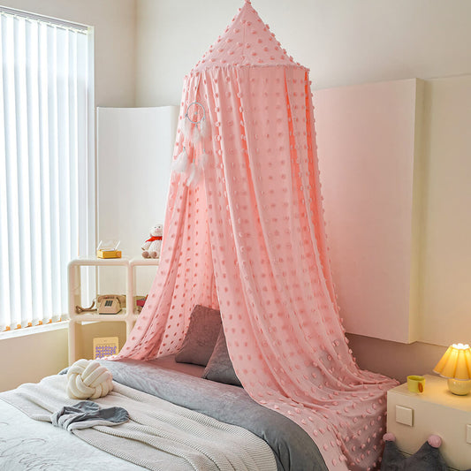Blush pink pom pom kids bed canopy hanging beside a child’s bed