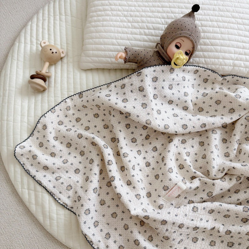 A baby doll and teddy bear sleep comfortably under a pure cotton muslin blanket with a miniature floral print.
