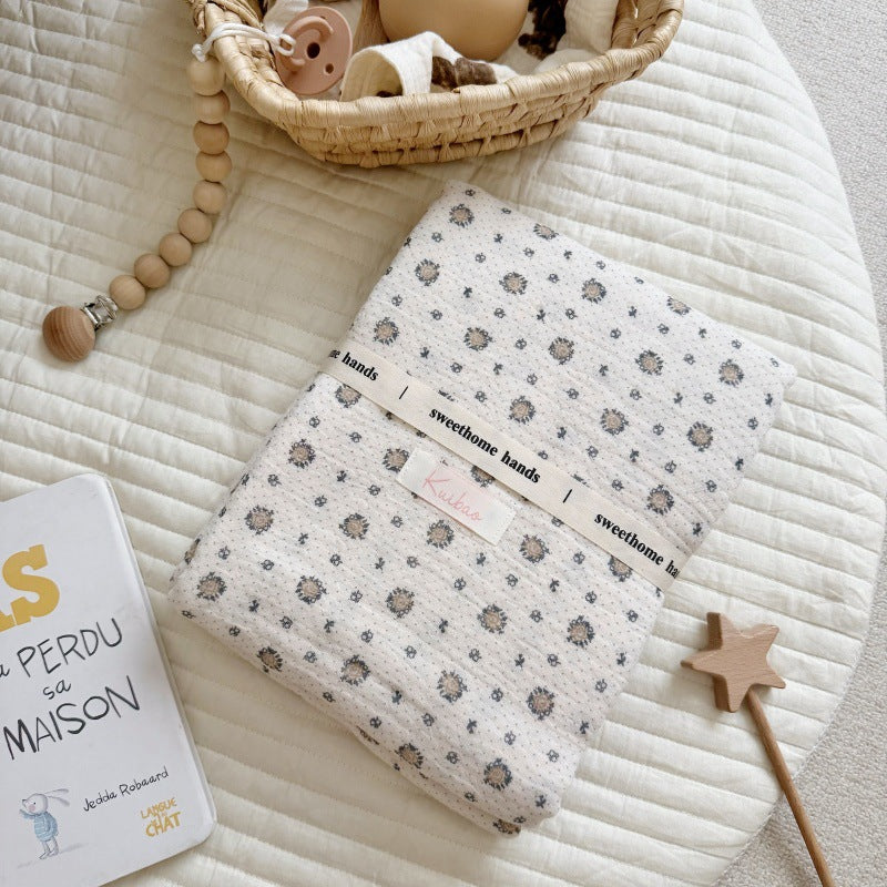 A neatly folded pure cotton muslin blanket with a brand tag, highlighting the beautiful vintage floral print and premium quality.