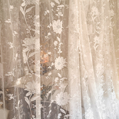 Sheer curtain with floral embroidery in a soft color palette.