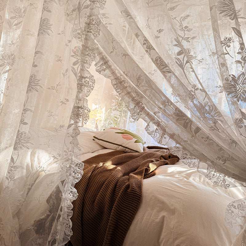 Floral lace curtains with a pillow and blanket in the foreground