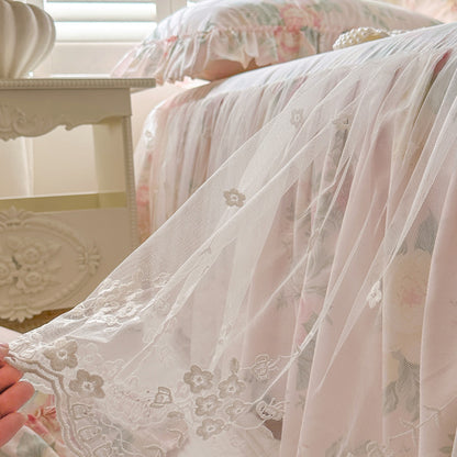 Close-up of the intricate white embroidery on the Vintage Blush lace bed skirt, held to show the mesh texture.