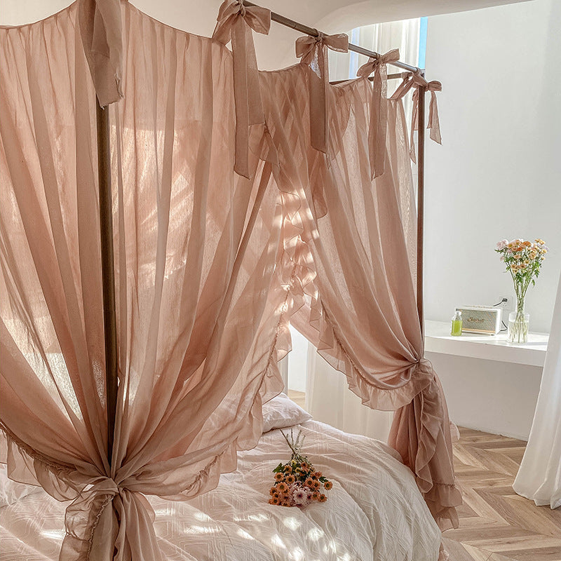 A close-up of the light coffee ruffled drapes, tied with bows at the top of a 4-poster bed frame, highlighting the soft fabric and delicate design.