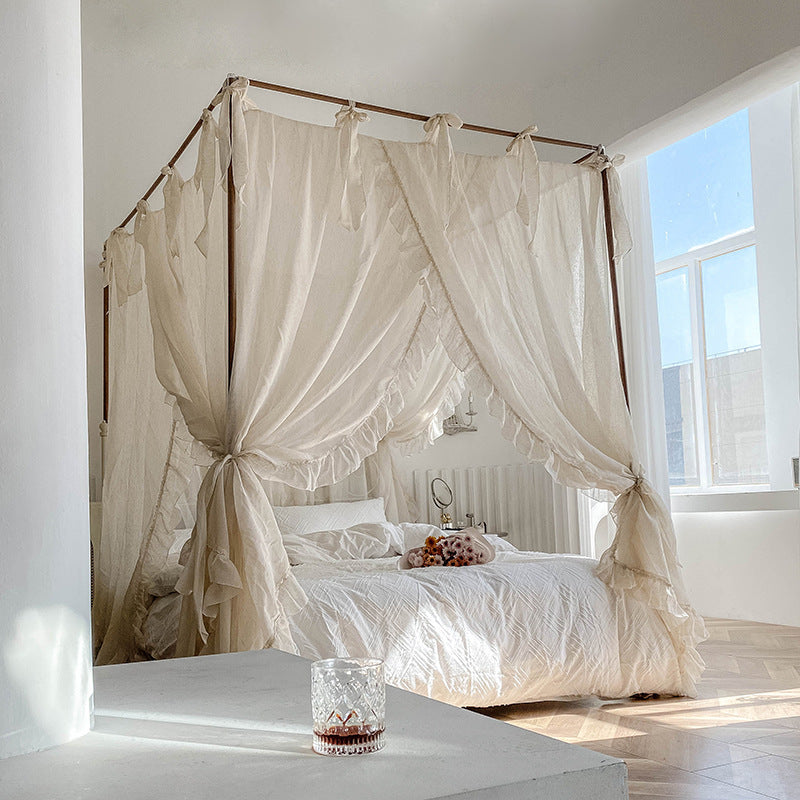 A full view of the natural linen-colored sheer lace bed canopy curtains on a 4-poster bed, creating a serene and minimalist bedroom look with abundant natural light.