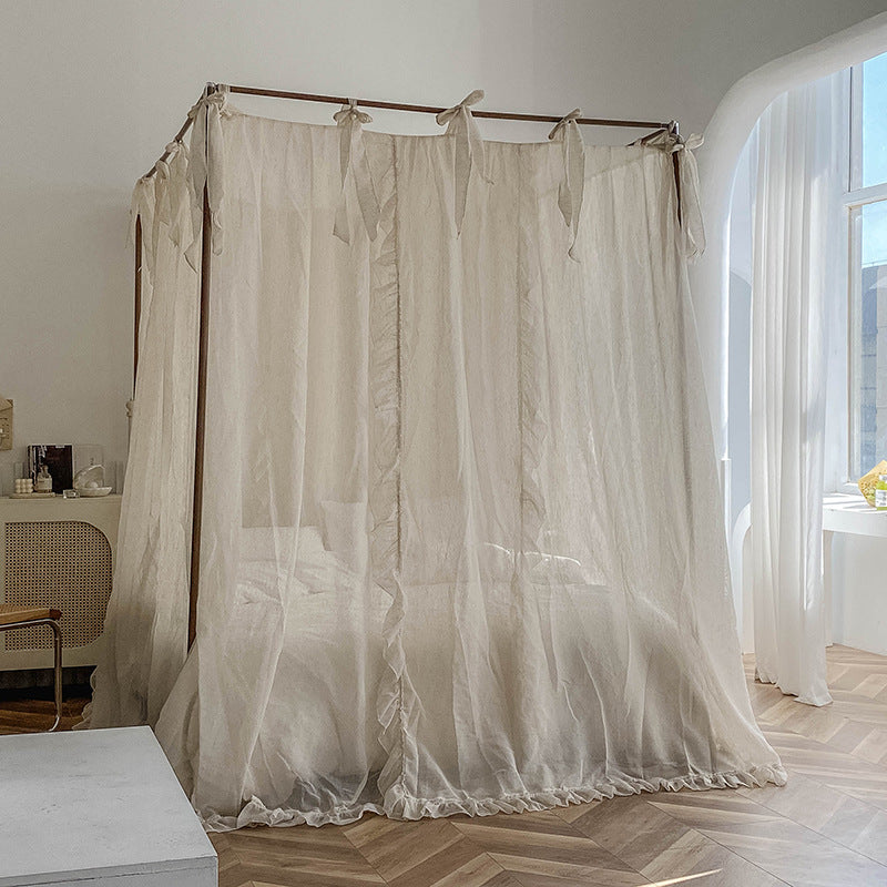 The natural linen sheer lace bed canopy pulled to fully enclose the bed, offering a feeling of privacy and tranquility, while light filters through the sheer fabric.