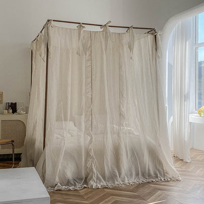 The natural linen sheer lace bed canopy pulled to fully enclose the bed, offering a feeling of privacy and tranquility, while light filters through the sheer fabric.