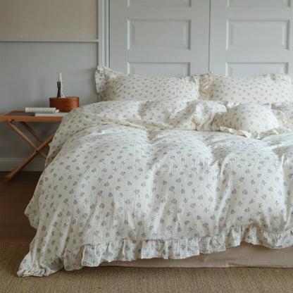 Blue rosebud duvet cover set styled on a full bed with soft ruffled edges and matching pillowcases