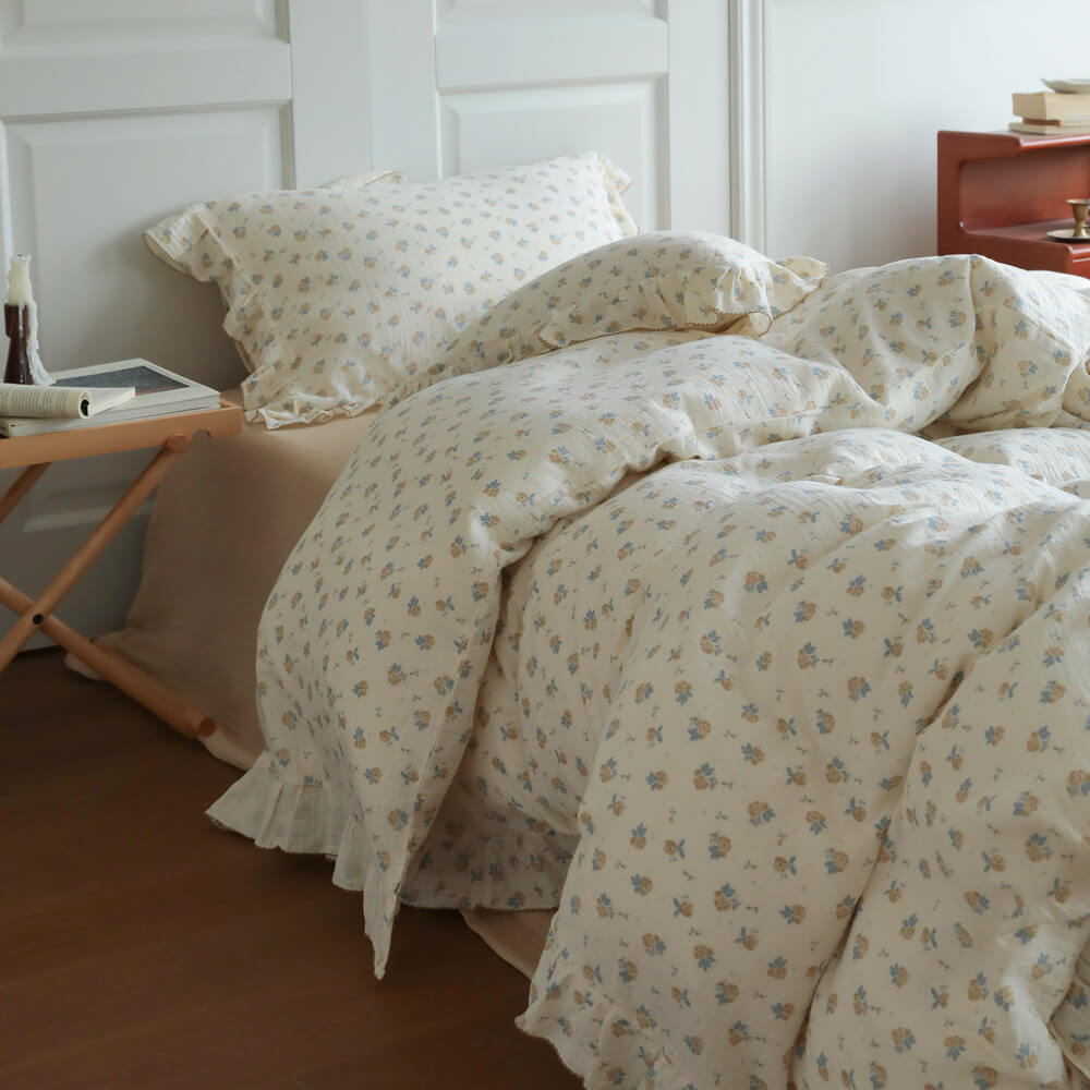 Ivory cotton muslin duvet cover with tiny blue rosebuds, relaxed folds, and ruffled trim
