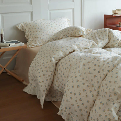 Ivory cotton muslin duvet cover with tiny blue rosebuds, relaxed folds, and ruffled trim