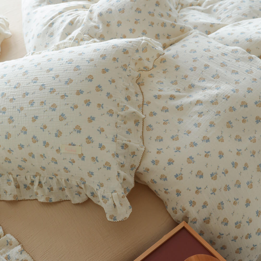 Ruffled pillowcase and duvet cover in ivory cotton muslin with tiny blue rosebud pattern