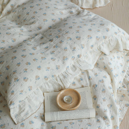 Cotton muslin blue rosebud bedding detail with light crinkles, ruffled trim, and ivory base
