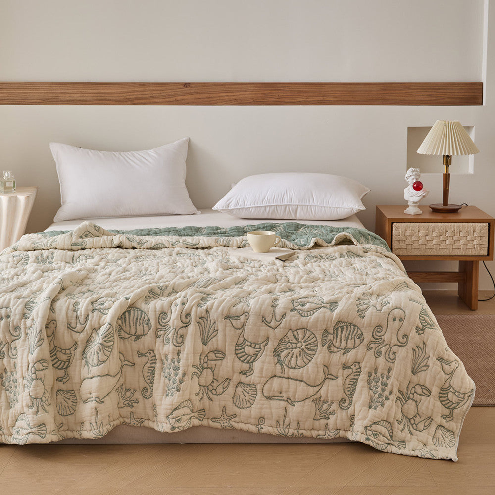 Full bed view of ivory sea life cotton jacquard blanket with muted green reverse side