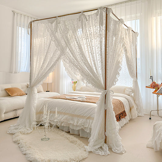 Bedroom with a canopy bed draped in white lace curtains, surrounded by neutral decor.